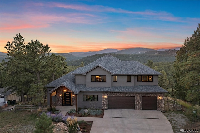 view of front of property with roof with shingles, an attached garage, fence, a mountain view, and driveway