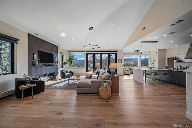 living room with light wood-type flooring, plenty of natural light, a premium fireplace, and visible vents