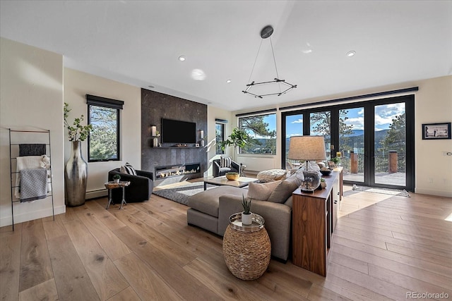 living area with light wood-style flooring, a high end fireplace, baseboards, french doors, and baseboard heating