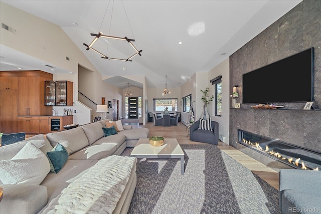 living room featuring recessed lighting, visible vents, light wood-style floors, a tiled fireplace, and an inviting chandelier