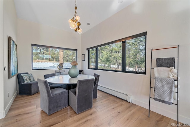 dining space featuring a chandelier, a baseboard radiator, baseboards, and light wood finished floors