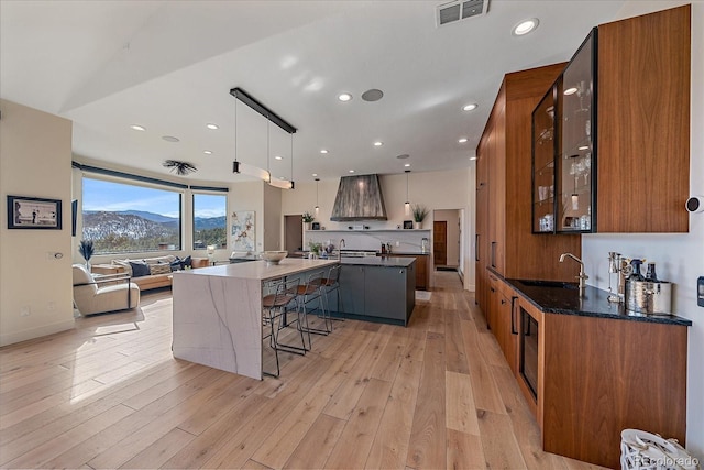 kitchen featuring premium range hood, a large island, light wood-type flooring, and visible vents