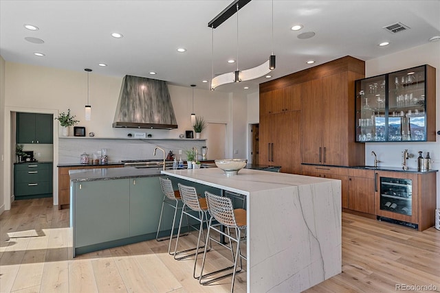 kitchen featuring light wood finished floors, wine cooler, custom exhaust hood, and visible vents