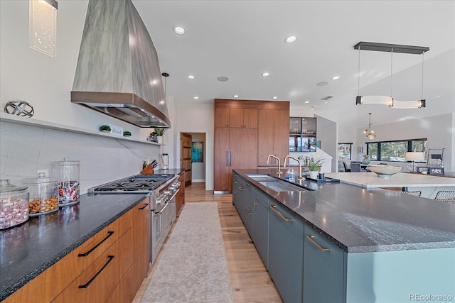 kitchen with a spacious island, a sink, stainless steel range, modern cabinets, and island exhaust hood