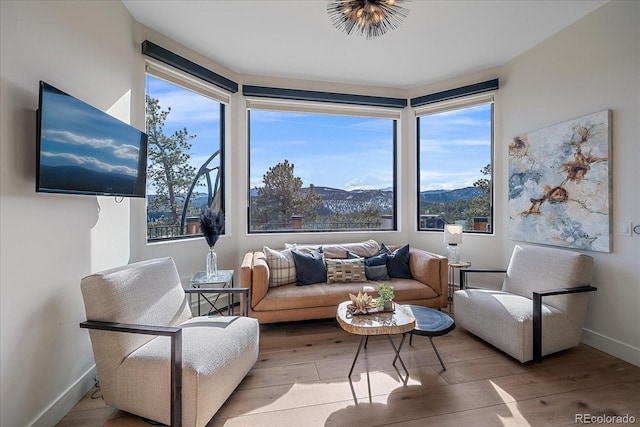 sitting room with a mountain view, baseboards, and wood finished floors