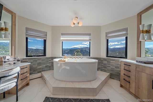 bathroom featuring a wainscoted wall, a freestanding tub, vanity, and tile walls