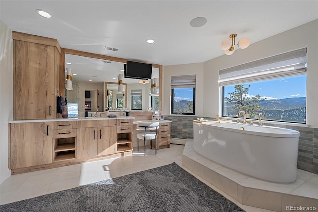 full bathroom with tile patterned flooring, vanity, visible vents, a freestanding bath, and tile walls