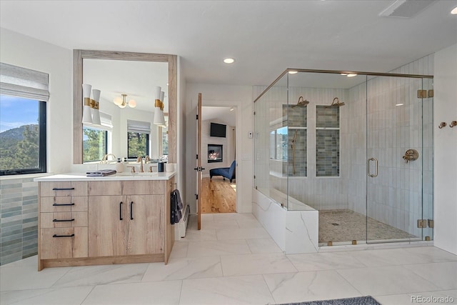 bathroom featuring a stall shower, vanity, a large fireplace, and ensuite bathroom