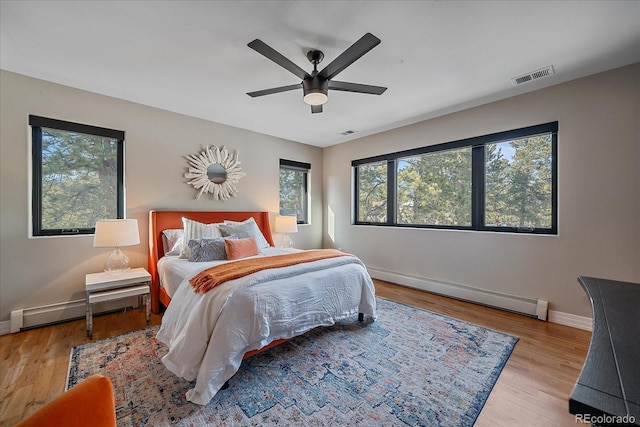 bedroom featuring a baseboard heating unit, multiple windows, a baseboard radiator, and visible vents