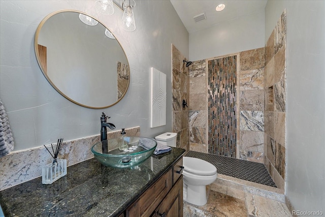 full bathroom with stone tile floors, visible vents, toilet, vanity, and walk in shower