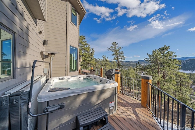 deck featuring a hot tub, a grill, and a mountain view