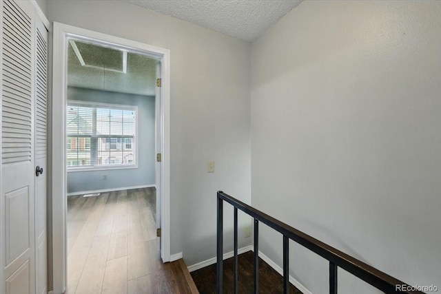 3525 Queen Anne Way, Colorado Springs, CO 80917 - hallway featuring attic access, a textured ceiling, dark wood-style flooring, an upstairs landing, and baseboards