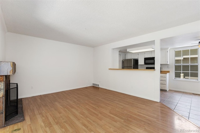 2013 S Helena St Unit B, Aurora, CO 80013 - unfurnished living room featuring light wood-style flooring, ceiling fan, and a textured ceiling