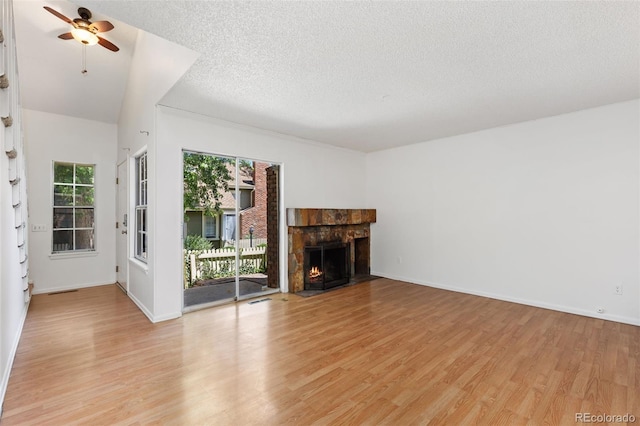 2013 S Helena St Unit B, Aurora, CO 80013 - unfurnished living room featuring light wood finished floors, a ceiling fan, a lit fireplace, and a textured ceiling