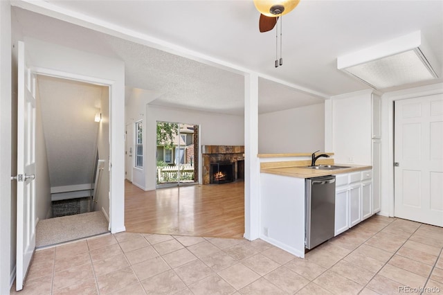 2013 S Helena St Unit B, Aurora, CO 80013 - kitchen featuring stainless steel dishwasher, light countertops, light tile patterned flooring, white cabinets, and a lit fireplace