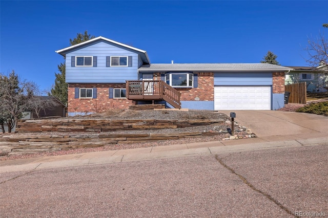 tri-level home with a garage, brick siding, concrete driveway, and stairs