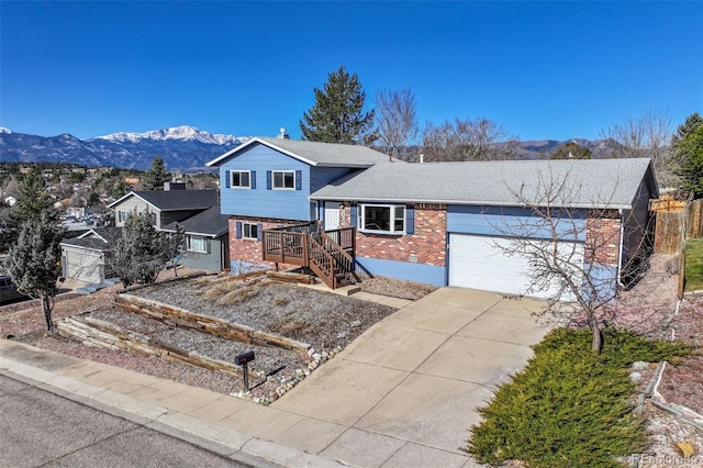 tri-level home featuring concrete driveway, a mountain view, a garage, and brick siding