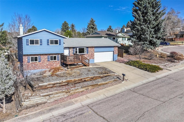 tri-level home featuring brick siding, driveway, a chimney, and a garage