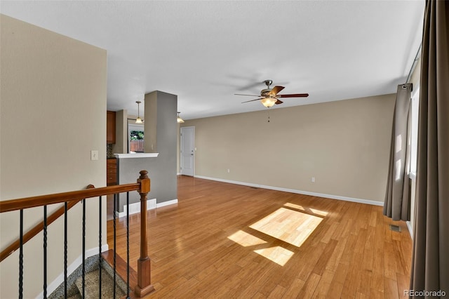 empty room with visible vents, baseboards, light wood finished floors, and ceiling fan