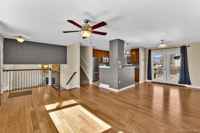 unfurnished living room with french doors, baseboards, light wood-style floors, and ceiling fan