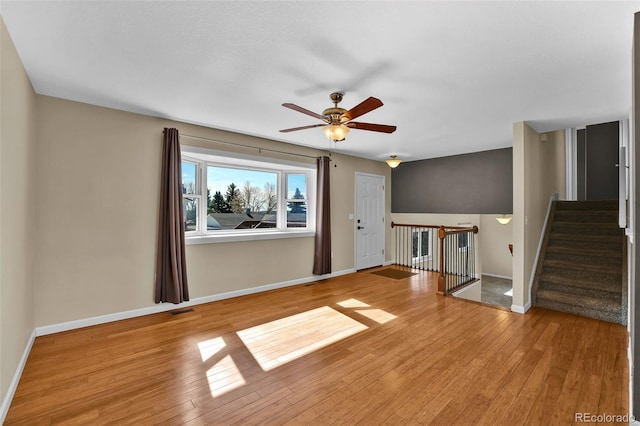 unfurnished living room with hardwood / wood-style floors, visible vents, baseboards, and ceiling fan