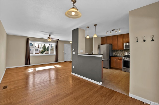 kitchen with dark countertops, visible vents, decorative backsplash, light wood-style flooring, and appliances with stainless steel finishes