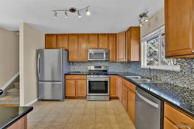 kitchen with light tile patterned floors, brown cabinetry, a sink, stainless steel appliances, and tasteful backsplash