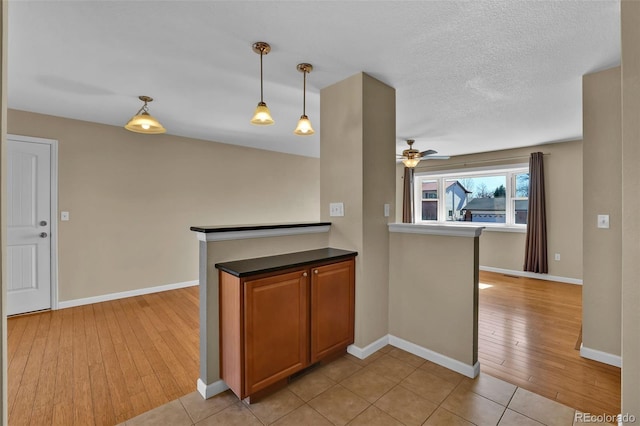 kitchen featuring baseboards, pendant lighting, light wood-style flooring, and a ceiling fan