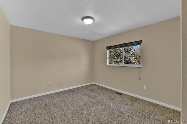 spare room featuring visible vents, carpet floors, a textured ceiling, and baseboards