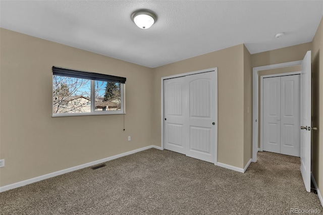 unfurnished bedroom featuring a closet, baseboards, visible vents, and carpet floors