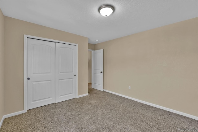 unfurnished bedroom with a closet, a textured ceiling, baseboards, and carpet