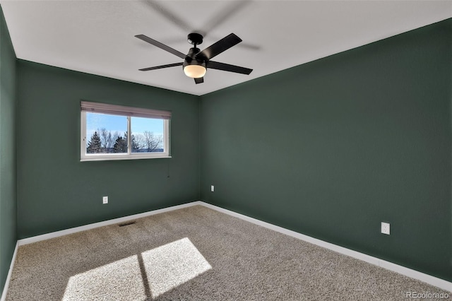 carpeted spare room featuring visible vents, baseboards, and ceiling fan