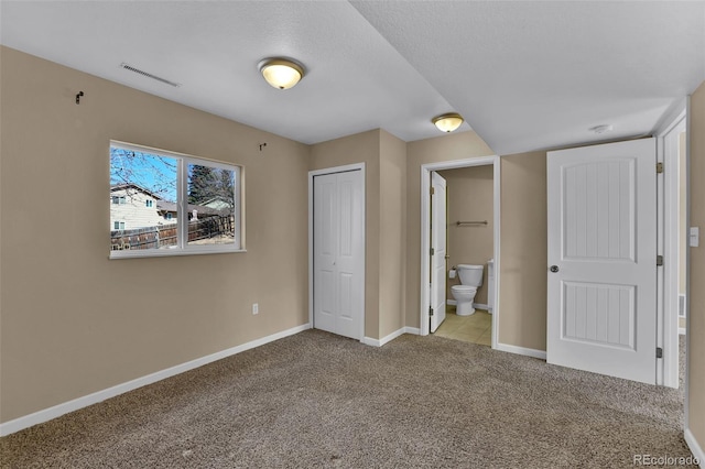 unfurnished bedroom featuring visible vents, ensuite bathroom, a closet, carpet flooring, and baseboards