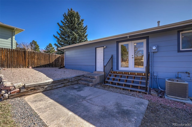 entrance to property featuring central AC unit, fence, and a patio area