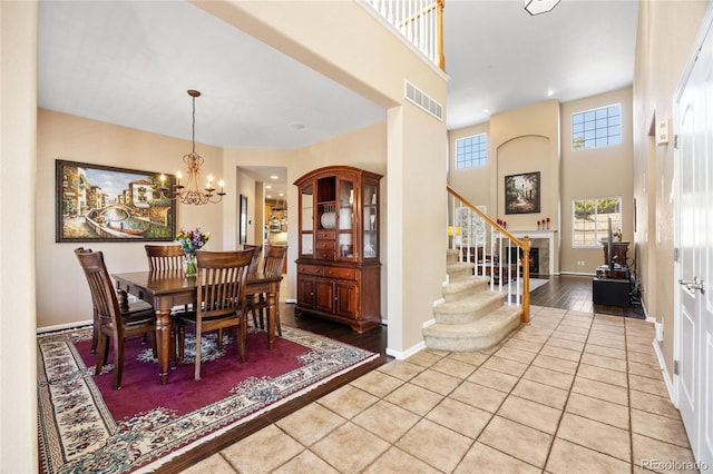 dining area featuring light hardwood / wood-style floors, a high ceiling, and a notable chandelier