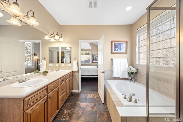 bathroom with vanity, plenty of natural light, and a relaxing tiled tub