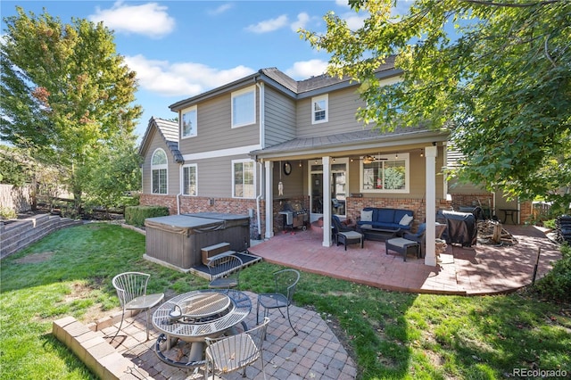 back of property with a yard, an outdoor living space with a fire pit, a hot tub, and a patio