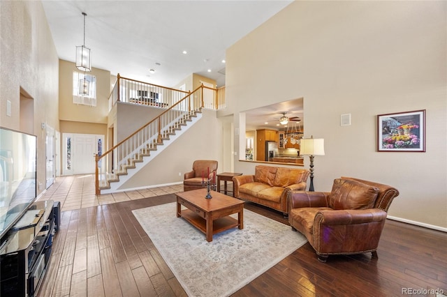 living room featuring hardwood / wood-style floors, ceiling fan, and a high ceiling