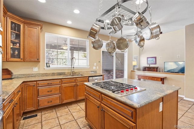 kitchen featuring a kitchen island, light stone countertops, appliances with stainless steel finishes, and sink