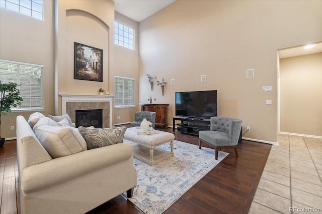 6987 Esperanza Dr, Castle Pines, CO 80108 - living area featuring a towering ceiling, baseboards, a glass covered fireplace, and wood finished floors