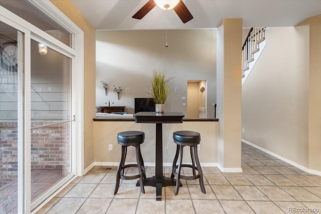 6987 Esperanza Dr, Castle Pines, CO 80108 - kitchen featuring a ceiling fan, tile patterned floors, baseboards, and a kitchen breakfast bar