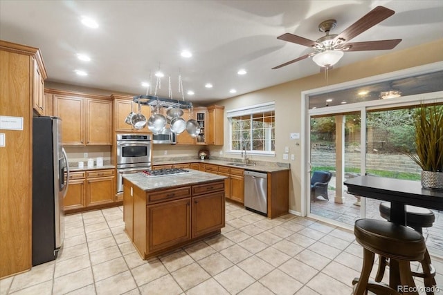 6987 Esperanza Dr, Castle Pines, CO 80108 - kitchen with stainless steel appliances, light tile patterned floors, recessed lighting, a center island, and light stone counters