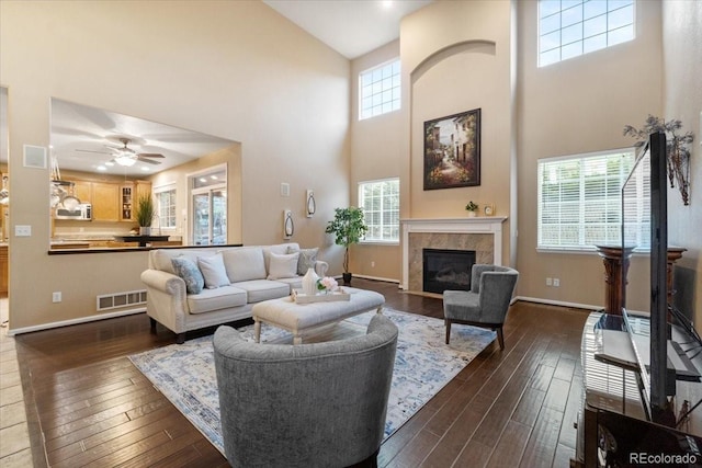 6987 Esperanza Dr, Castle Pines, CO 80108 - living room featuring a towering ceiling, dark wood-style flooring, a fireplace with flush hearth, baseboards, and a ceiling fan