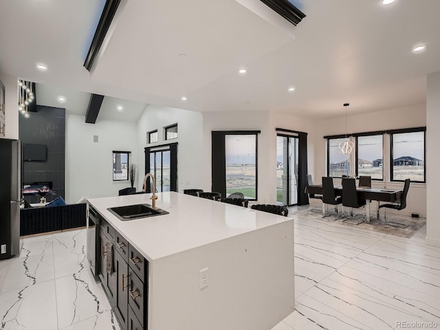 kitchen with sink, a kitchen island with sink, stainless steel refrigerator, black dishwasher, and vaulted ceiling