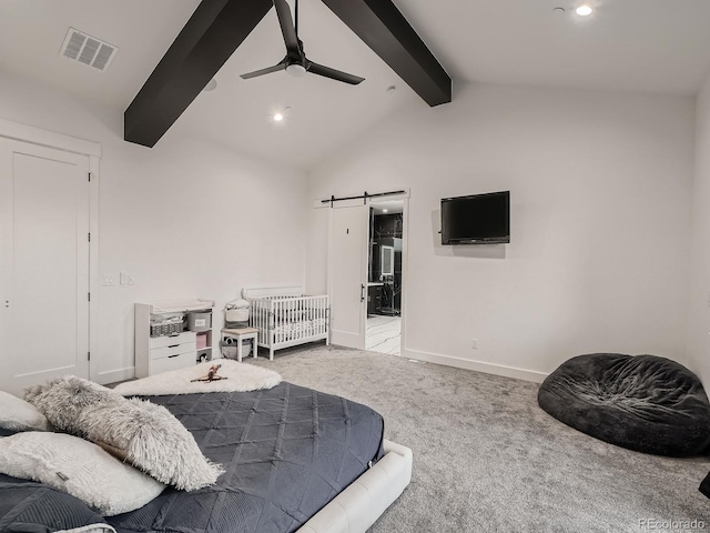 bedroom featuring a barn door, ceiling fan, vaulted ceiling with beams, ensuite bath, and light carpet