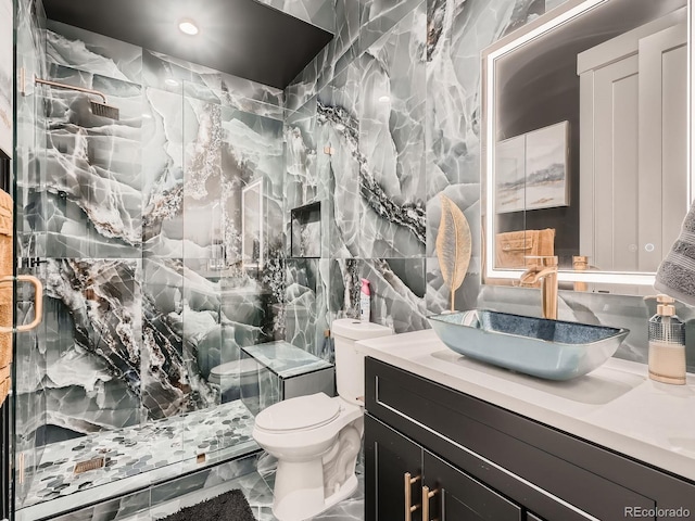 bathroom featuring vanity, tile walls, a shower with shower door, and toilet