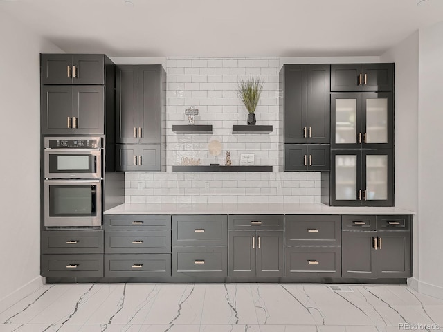 kitchen featuring gray cabinetry, double oven, and tasteful backsplash