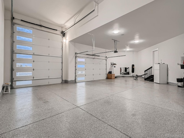 garage with a garage door opener and white refrigerator