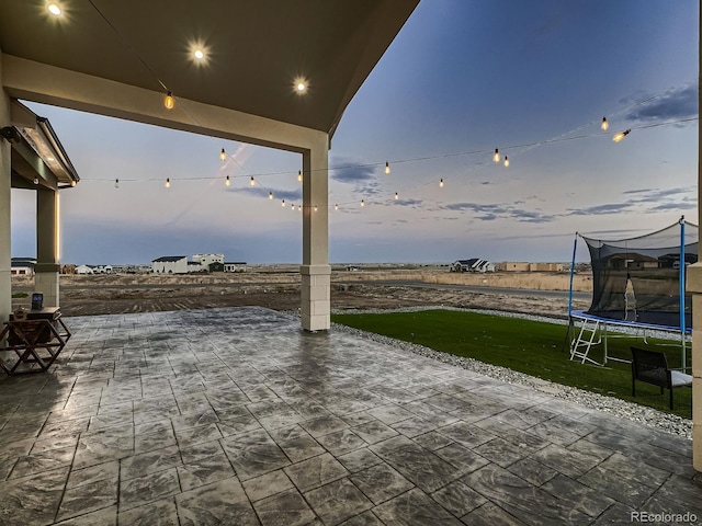 patio terrace at dusk with a trampoline and a yard