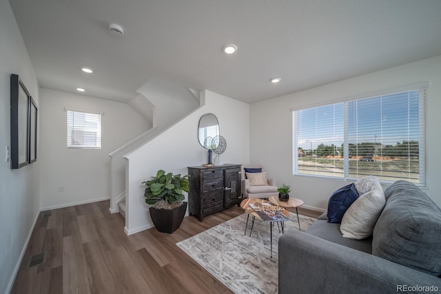 living area with wood finished floors, visible vents, baseboards, recessed lighting, and stairs